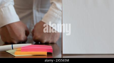 Foglio di carta bianco e penna a sfera su adesivi di carta multicolore primo piano su sfondo sfocato dell'indice dell'uomo di mezza età Foto Stock