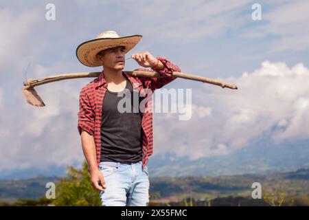 stile di vita: primo piano di un agricoltore con zappa sulla spalla che guarda il cielo Foto Stock
