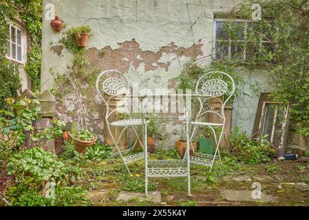 Vecchio tavolo e sedie in metallo da giardino in un giardino rustico Foto Stock