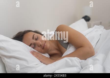 camera da letto tranquilla, una giovane donna dorme profondamente sotto la coperta su un comodo materasso ortopedico. Foto Stock