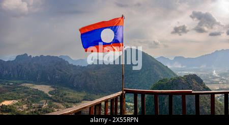 Laos, Nationalflagge mit Panorama vom Pha Ngern View Point Die Laotische Nationalflagge weht am Pha Ngern Aussichtspunkt mit Panorama auf Vang Vieng und die Kartlandschaft. Provinz Vientiane, Demokratische Volksrepublik Laos, 11.01.2024 *** Laos, bandiera nazionale con panorama dal punto di vista di Pha Ngern la bandiera nazionale laotiana vola al punto di vista di Pha Ngern con panorama di Vang Vieng e del paesaggio di Kart Provincia di Vientiane, Repubblica democratica dei popoli del Laos, 11 01 2024 Copyright: JOKER/WalterxG.xAllgöwer JOKER240111464586 Foto Stock