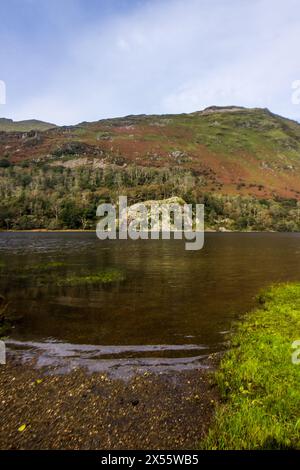 Montagne che si innalzano sopra le calme acque del lago Llyn Gwynant in una soleggiata giornata autunnale nel Parco Nazionale di Eryri nel Galles settentrionale Foto Stock