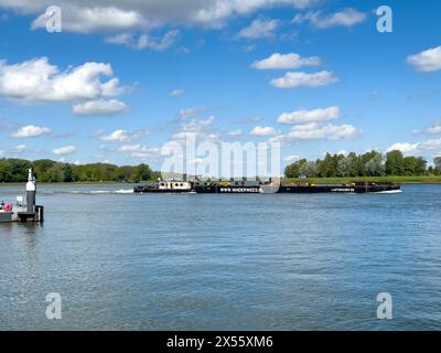 Dordrecht, Paesi Bassi - 29 aprile 2024: Navigazione interna, Olanda. Un molo galleggiante, spesso sotto forma di una o più chiatte di ferro, navigando oltre Dordre Foto Stock