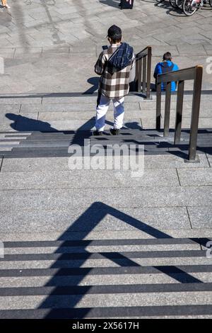 Uomo con giacca a plaid in piedi alle scale dal piazzale della stazione alla cattedrale, Colonia, Germania. Mann mit karrierter Jacke steht an der tre Foto Stock