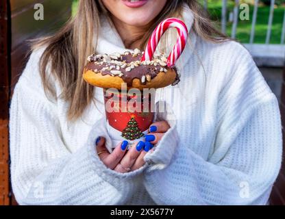 ragazza che tiene un frullato con ciambelle e altri dolci in un barattolo Foto Stock