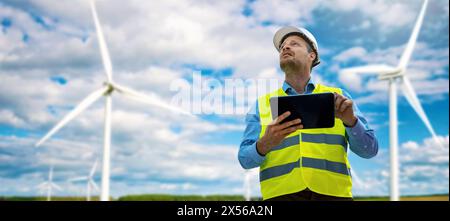 ingegnere con tablet digitale che lavora al parco delle turbine eoliche. produzione di energia sostenibile. spazio di copia banner Foto Stock