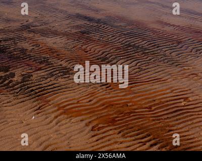 onde naturali ornamenti di sabbia bagnata arancione Foto Stock