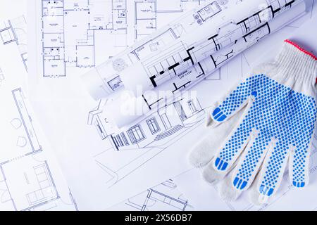 Attrezzi del costruttore sullo schema della casa. Preparandosi a costruire una casa. Guanti e blueprint per costruttori.. Foto Stock