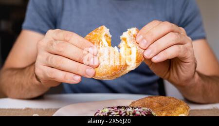 Uomo che mangia ciambelle con gelatina di albicocca. Ciambella ceca in primo piano. Foto Stock