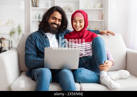 Giovane coppia che utilizza un notebook in un luminoso salotto Foto Stock