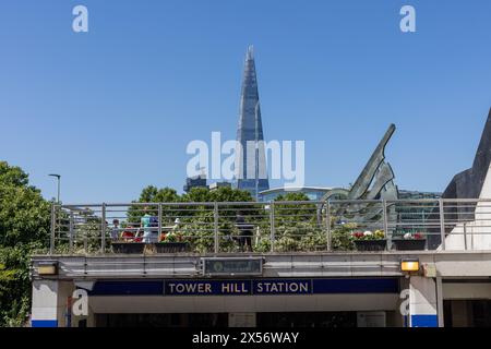 Londra, Inghilterra - 19 giugno 2022: Ingresso alla stazione della metropolitana Tower Hill con piattaforma panoramica con persone in cima. Edificio alto, il frammento visibile sul retro Foto Stock