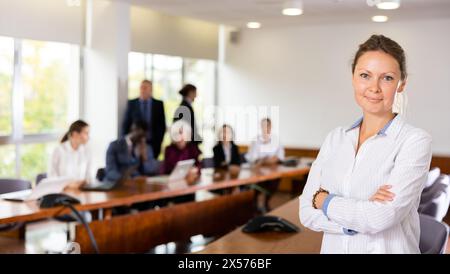 Donna d'affari bionda bianca di mezza età sorridente che posa Foto Stock