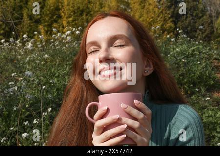 La bella donna con i capelli rossi si gode una tazza di caffè Foto Stock