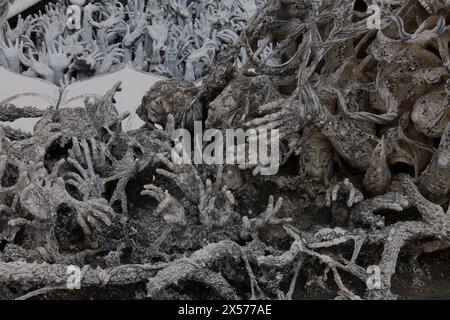 Sculture di mani e volti che raggiungono l'alto al Tempio bianco, Wat Rong Khun, nella provincia di Chiang Rai in Thailandia Foto Stock