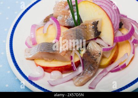 Sono servite fette di aringa leggermente curata con patate fritte e cipolle Foto Stock