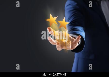 Uomo con stelle virtuali su sfondo nero, primo piano. Punteggio di soddisfazione del cliente Foto Stock