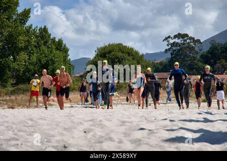 Sabaris, Baiona, Pontevedra, Spagna; 15 luglio, 2023; i concorrenti di triathlon corrono attraverso la sabbia della spiaggia di Ladeira verso l'acqua per iniziare il nuoto Foto Stock