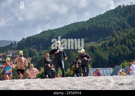 Sabaris, Baiona, Pontevedra, Spagna; 15 luglio, 2023; i concorrenti di triathlon corrono attraverso la sabbia della spiaggia di Ladeira verso l'acqua per iniziare il nuoto Foto Stock