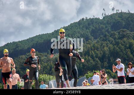 Sabaris, Baiona, Pontevedra, Spagna; 15 luglio, 2023; i concorrenti di triathlon corrono attraverso la sabbia della spiaggia di Ladeira verso l'acqua per iniziare il nuoto Foto Stock