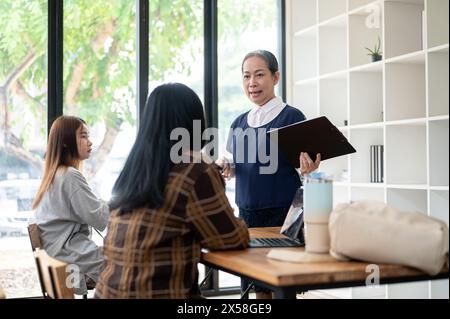 Una professoressa asiatica o professoressa professionista ed esperta che insegna agli studenti in classe, spiegando una lezione, in piedi davanti Foto Stock