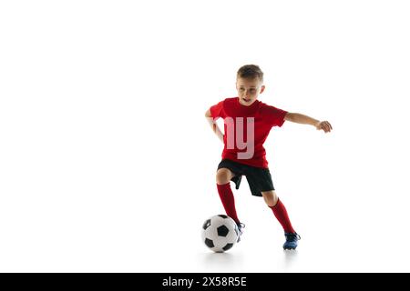 Bambino atletico e sportivo con tecnica di dribbling in movimento su sfondo bianco da studio. Scatto dinamico. Foto Stock