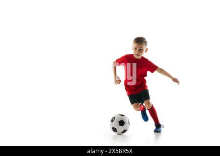 Atletico e sportivo ragazzo con tecnica di dribbling uniforme in movimento su sfondo bianco da studio. Scatto dinamico. Foto Stock