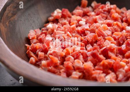 Cubi di jamon tradizionali spagnoli in una ciotola di legno da vicino. Ingrediente da cucina a base di carne. Foto Stock