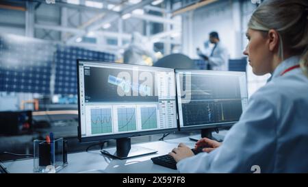 Un ingegnere donna utilizza il computer per analizzare il satellite, calcolare il tracciamento della traiettoria orbitale. Aerospace Agency International Space Mission: Scienziati che lavorano alla costruzione di veicoli spaziali. Sulla spalla Foto Stock