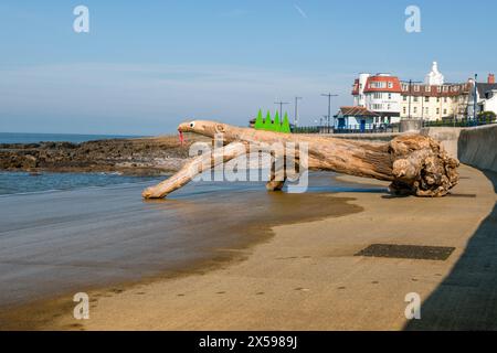 Un ceppo d'albero lavato sul lungomare di Porthcawl è stato decorato come una lucertola. Foto Stock