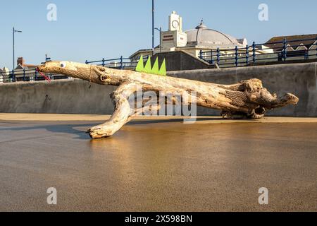 Un ceppo d'albero lavato sul lungomare di Porthcawl è stato decorato come una lucertola. Foto Stock