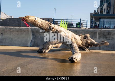 Un ceppo d'albero lavato sul lungomare di Porthcawl è stato decorato come una lucertola. Foto Stock