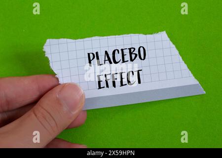 Parole con effetto placebo scritte su carta strappata con sfondo verde. Simbolo concettuale dell'effetto placebo. Copia spazio. Foto Stock