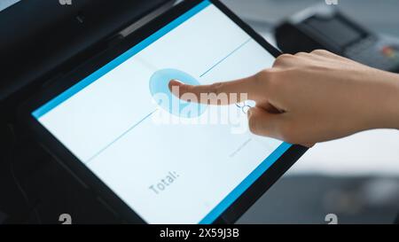 Close Up Shot of a Person Touching an Electronic Fingerprint Recognition Feature on a Digital Screen in Order to Make a Purchase in a Clothing Store. Customer Buying Items in Shop with Digital ID. Foto Stock