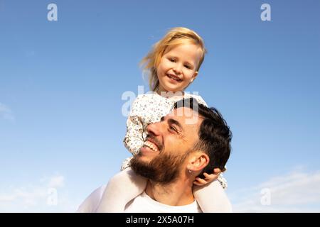 Ritratto di padre e figlia che giocano all'aperto su sfondo blu del cielo Foto Stock
