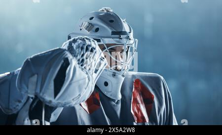 Ice Hockey Rink Arena: Ritratto di brutale portiere professionista, aspetto serio. Goalie concentrata, determinata a vincere. Campione di atleta sicuro. Scatto verticale primo piano Foto Stock
