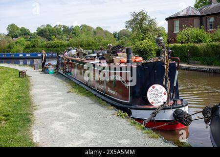 La barca stretta di Crafty Witch ormeggiava vicino a Ellesmere nello Shropshire sul canale Llangollen, con molti oggetti artigianali in vendita sul tetto della barca. Foto Stock