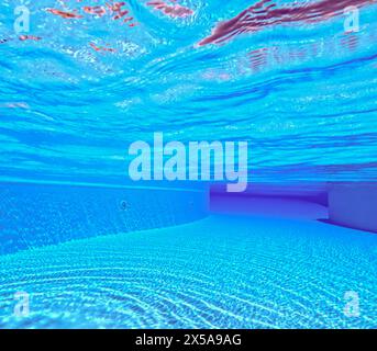 Una tranquilla scena subacquea in una piscina blu cristallina, con motivi luminosi che ballano sul piano della piscina Foto Stock