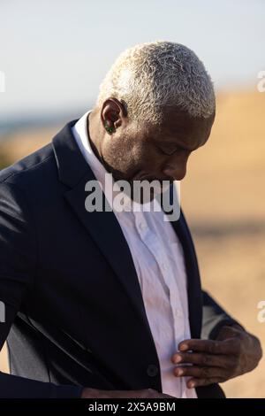 Uomo afroamericano con un'espressione premurosa, vestito da abbigliamento formale, che guarda in basso Foto Stock