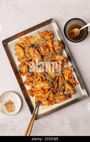 Dall'alto potrai ammirare le ali di pollo arrosto e le patatine fritte servite su un vassoio di metallo, catturato dall'alto. Foto Stock