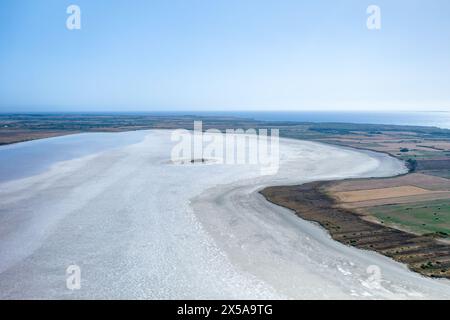 Una splendida fotografia aerea che cattura i tranquilli paesaggi di una salina in Sardegna, Italia, con campi agricoli a contrasto e il mare lontano Foto Stock