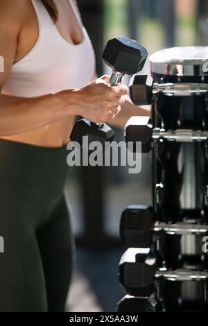 Un'immagine ravvicinata della mano di un'atleta mentre solleva un manubrio, focalizzata sul fitness a casa Foto Stock