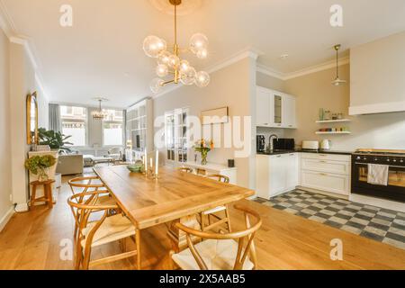 Un'invitante cucina open space e zona pranzo con tavolo da pranzo in legno, illuminazione moderna e interni accoglienti. Foto Stock