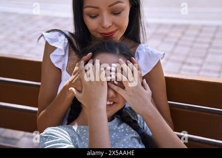 Ragazza con spettro autistico che si diverte con sua madre su una panchina in città Foto Stock