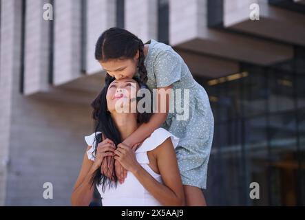 Ragazza con spettro autistico che abbraccia e bacia sua madre mentre cammina in città Foto Stock