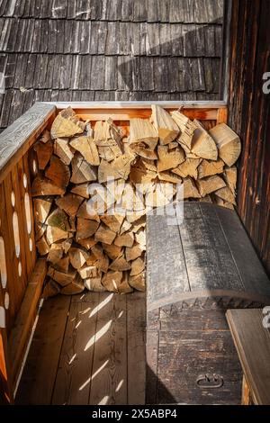 Dettaglio dell'antico portico in legno con pila di legna da ardere preparata per l'inverno e panca in legno d'epoca Foto Stock