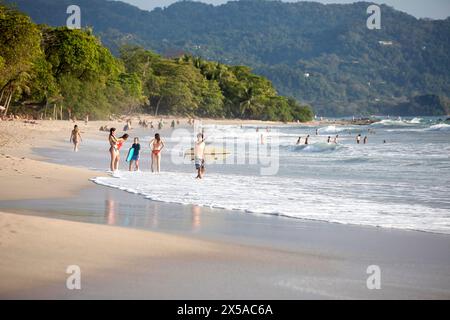 Turisti con tavole da surf sulla spiaggia di Santa Teresa con foresta pluviale tropicale sul retro che si godono durante le vacanze di natale, penisola di Nicoya, Costa rica Foto Stock