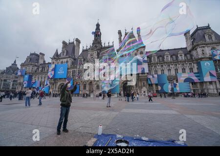 Parigi, Francia. 8 maggio 2024. Un artista di strada soffia bolle di sapone di fronte all'Hotel de Ville, che è adornato da poster gigante come città ospite di Parigi per le Olimpiadi e le Paralimpiadi del 2024. Crediti: amer ghazzal/Alamy Live News Foto Stock