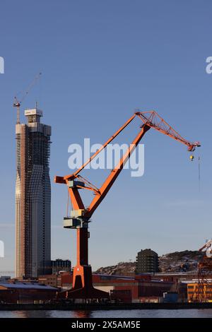 gothenburg, Svezia - 04 febbraio 2023: Costruzione di un alto edificio Karlatornet. Telaio in calcestruzzo parzialmente coperto da finestre. Vecchia gru portuale in anticipo Foto Stock