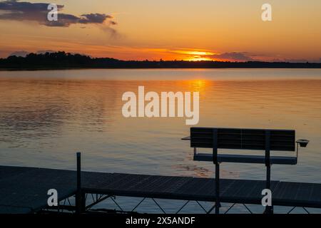 Scena serale in un lago di Bemidji, Minnesota, con una banchina vuota e alcune increspature sull'acqua riflettente. Foto Stock