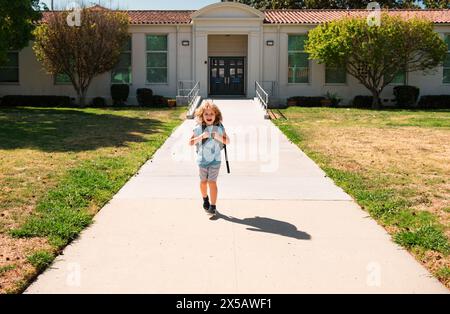 Schoolchild che corre sul parco giochi alla fine della lezione. Vocazione scolastica. Concetto di educazione dei bambini. Foto Stock